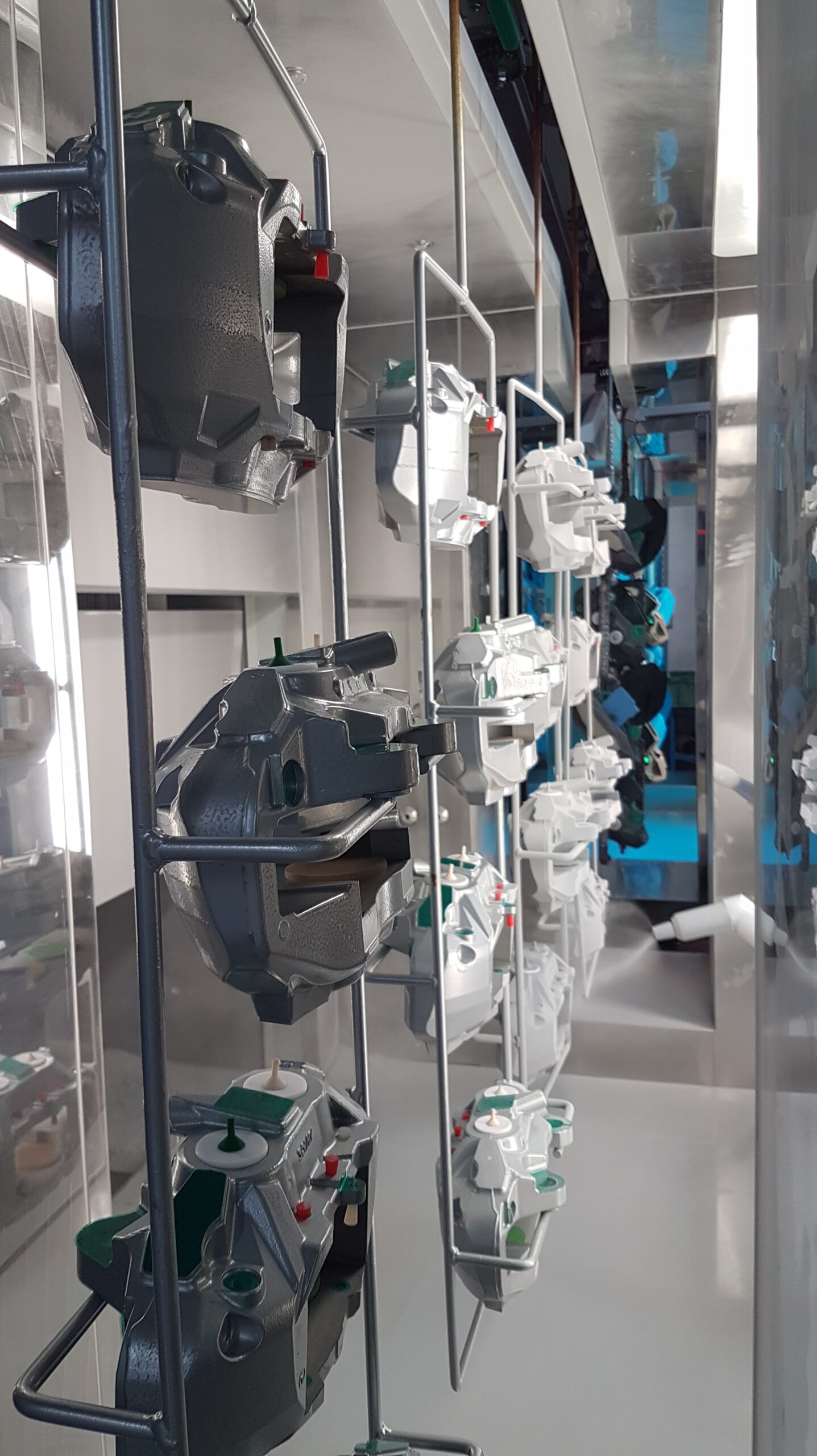 Close-up of complex metal housings suspended on the overhead conveyor system